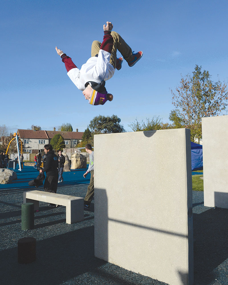 Ein Mann kippt in einem Parkour-Park auf den Kopf.